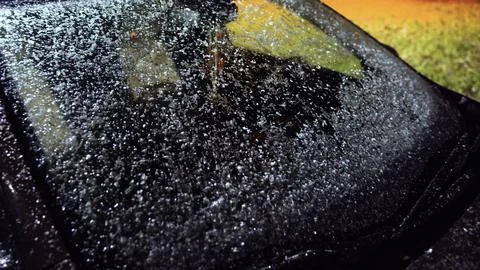 Falling snow on a car windshield at night. Real snowflakes falling towards car Stock Photos