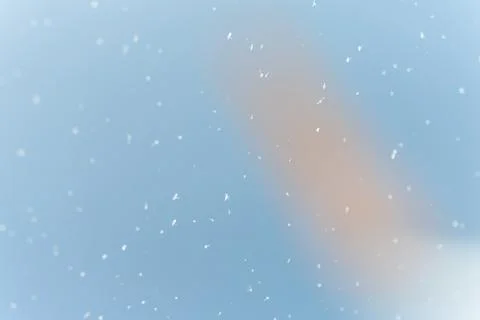Falling snow creating bokeh against blue gradient background 스톡 사진
