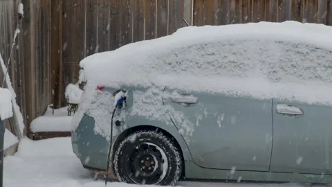 Falling snow electric parked car in backyard by fence Stock Footage 295919414