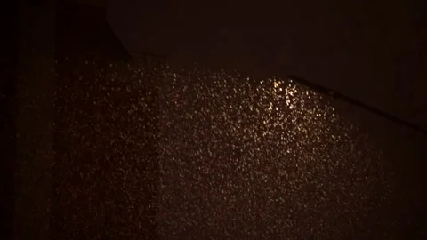 Falling snow illuminated by warm srteet light in night city Stock Footage 143528010