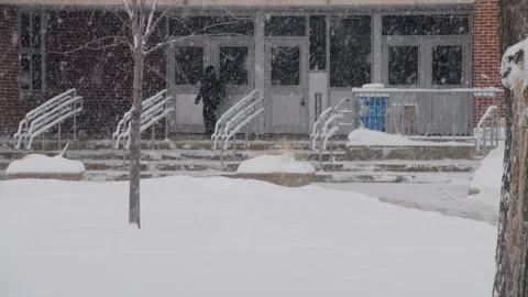 Falling snow with person entering school building in winter Stock Footage 295915751