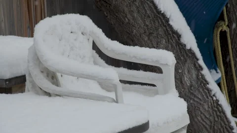 Falling snow plastic deck chairs in backyard by tree Stock Footage 295919766