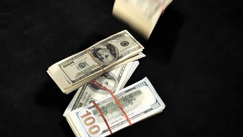 Falling stacks of dollars from a high angle on a black table in slow motion. Stock Footage 129786499