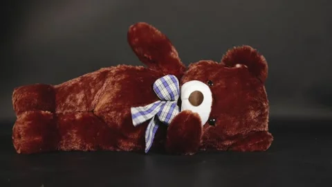 Falling teddy bear on black background symbolizing lost childhood and social Stock Footage 314719250