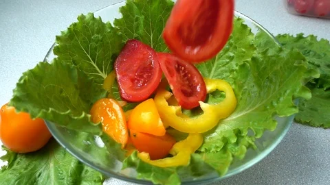 The falling tomatoes on lettuce leaves. Slow motion. Stock-Footage 108949655