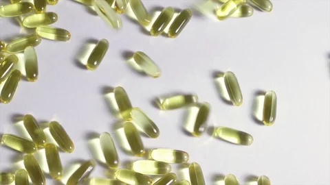 Falling transparent Omega 3, vitamins gel capsules and tablets on a white table. Stock Footage 101669778