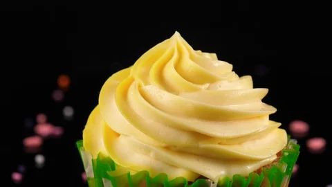 Falling various multicolored sugar sprinkles on yellow Cupcake, close-up view Stock Footage 91029403