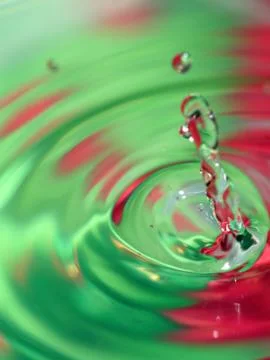 Falling water drop and nice splash on colorful background. Stock Photos