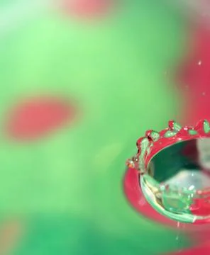 Falling water drop and nice splash on colorful background. Stock Photos