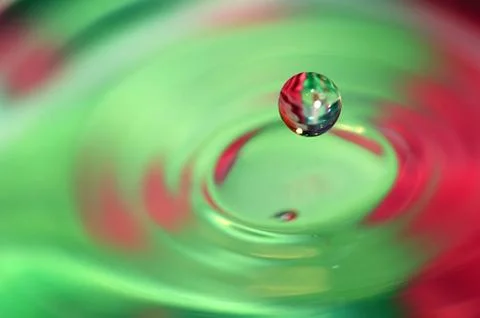 Falling water drop and nice splash on colorful background. Stock Photos