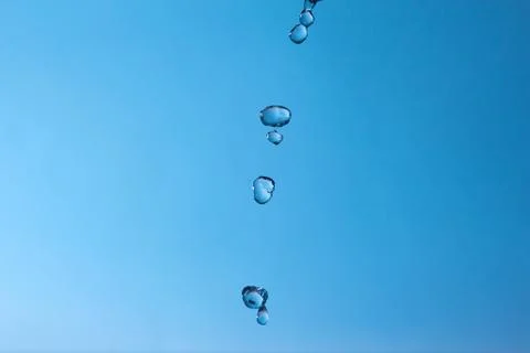Falling water drops on a blue background. Stock Photos