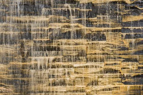 Falling water stream against stonework rough texture Foto stock