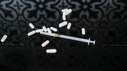 Falling White Capsules on thin syringe that lies on black glass Background, slow Vídeos de archivo 261894442