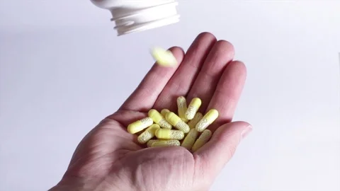 Falling yellow capsules and tablets of vitamin c into the palm of hand. Stock Footage 101681427