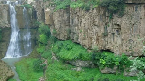 Falls Large Waterfall Cascading Over A Lush Green Cliff. Nature landscape Stock Footage 133353964