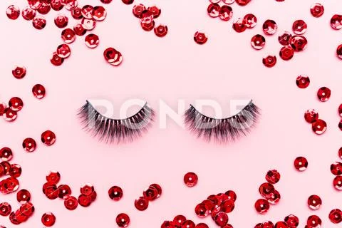 False eyelashes black color and red confetti lying on pink background. Beauty Stock Photos