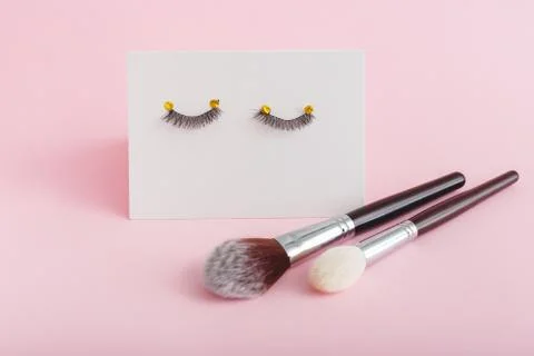 False eyelashes makeup brushes on pink background. Beauty products, cosmetics Stock Photos