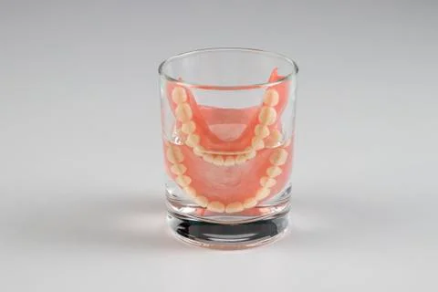 False teeth in a glass of water. Stock Photos
