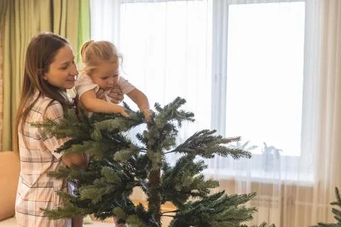 Family assembling, shaping hook-in artificial Christmas Tree at home Stock Photos