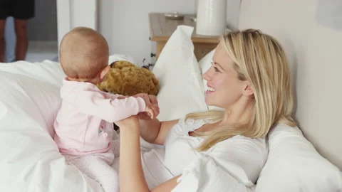 Family With Baby Daughter Having Fun Playing Games In Bed Together At Bedtime Stock Footage