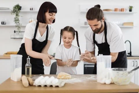 Family baking shared time in bright home kitchen with flour and smiles Stock Photos