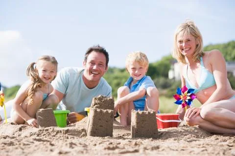 Family on beach making sand castles smiling Stock Photos