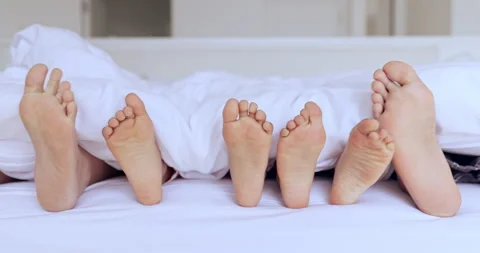 Child with bare feet in jeans. Lying on the bed. Foot barefoot