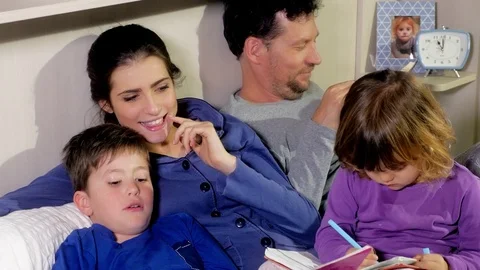 Family in bed reading books doing homework Stock Footage 74097250