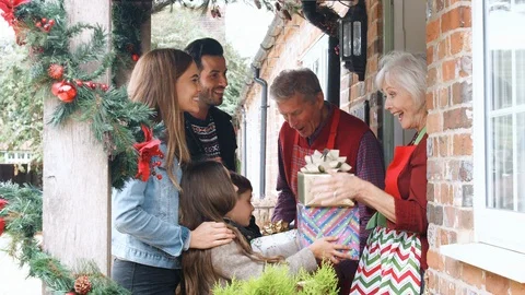 Family Being Greeted By Grandparents As They Arrive For Visit On Christmas Day Stock Footage