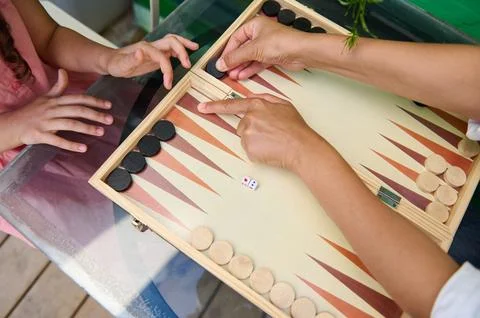 Family bonding over a game of backgammon with hands moving pieces on the boar Stock Photos