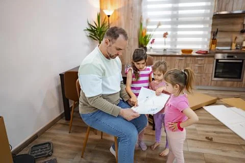 Family bonding while assembling new furniture in a cozy kitchen Stock Photos