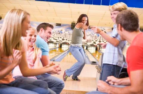 Family in bowling alley with two friends cheering and smiling Stock Photos