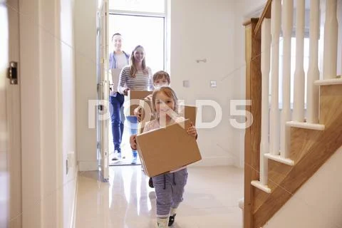 Family Carrying Boxes Into New Home On Moving Day
