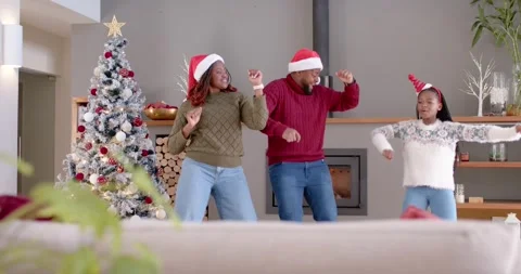 Family celebrating, dancing after camera clearing foreground, wearing Santa hats Stock Footage 343468559