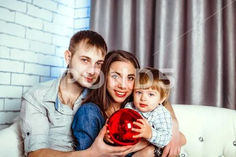 A family with a child sitting on the couch Stock Photos