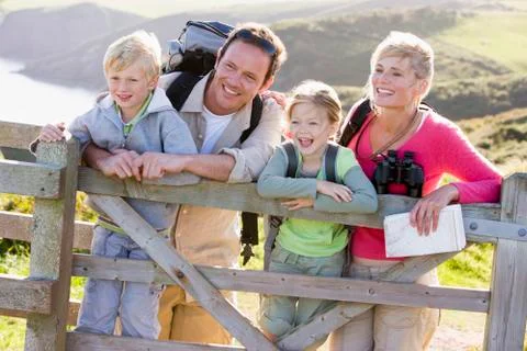 Family on cliffside path leaning on fence and smiling Stock Photos