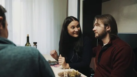 Family couple clings glasses and drinks while talking to friend at dinner table Stock Footage