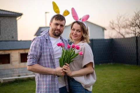 Family couple wearing bunny ears celebrating easter. husband gives his wife Stock Photos