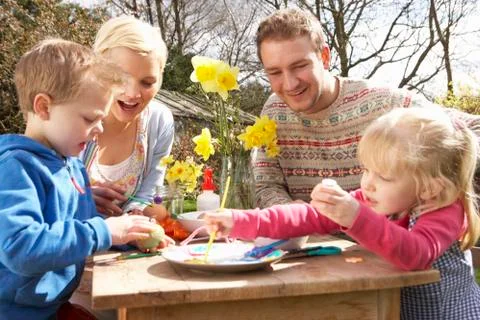 Family decorating easter eggs on table outdoors Stock Photos