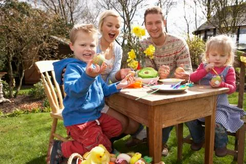 Family decorating easter eggs on table outdoors Stock Photos