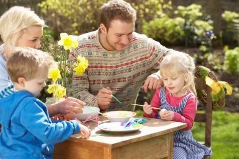 Family decorating easter eggs on table outdoors Stock Photos