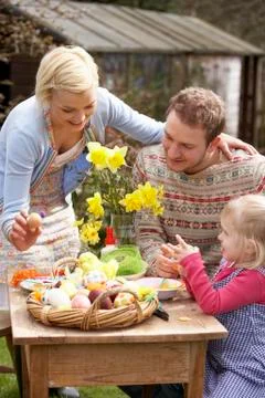 Family decorating easter eggs on table outdoors Stock Photos