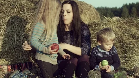 The family eats apples in a haystack in the field. Stock Footage 84186386