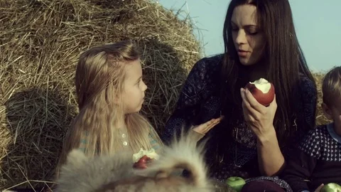 The family eats apples in a haystack in the field. Stock Footage 84186701