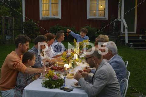 Family enjoying candlelight garden dinner party Stock Photos