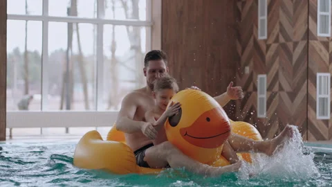 Family entertainment in swimming pool, father and little son are floating on Stock Footage 186617736