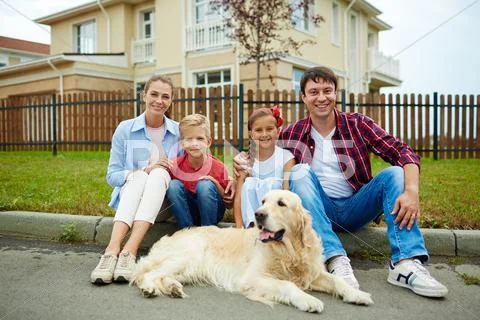 Family of four and their pet sitting by their new house Stock Photos