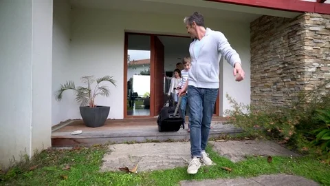Family of four loading car trunk to leave for vacation Stock Footage