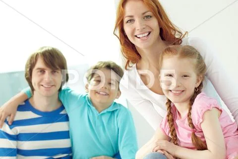 Family of four reading book together at home Stock Photos