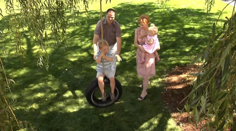 Family in front yard with tire swing Stock Footage